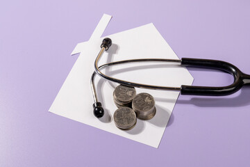 Home, Health & Wealth Concept – Paper House with Stethoscope and Coins on Desk