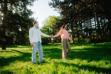 Couple joyfully exploring a sunlit park during a warm afternoon stroll