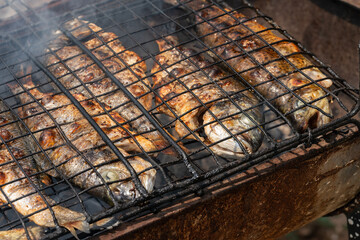 Fresh sea bass and sea bream from the Aegean Sea grilling over charcoal. This delicious, healthy meal is rich in omega-3 fatty acids and a cornerstone of the Mediterranean diet.