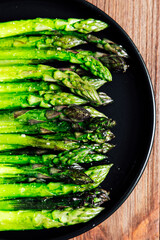 Fresh cooked asparagus arranged on a black plate ready to serve at a dinner table
