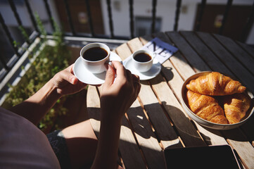 A serene morning setting featuring coffee and croissants on a wooden table. Ideal for enjoying a peaceful start to the day in a natural and fresh environment.