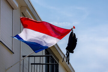 Official Netherlands flag with a school bag hanging outside the house along the street with blue...