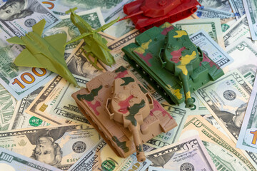 Financing US military spending. Toy tanks, aeroplane and helicopter on the background of American dollars. 