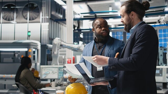 Team of inspectors consultants reviewing the solar power plant activity and production line, ensuring the correct manufacturing process. Master engineers examine factory equipment. Camera A.