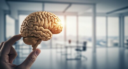 Conceptual brain representation held in hand against a modern office background; symbolizing knowledge and innovation.