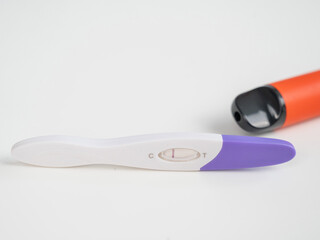 Pregnancy test and electronic cigarette and disposable vape on white table. 