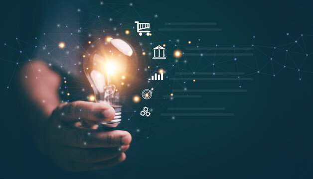 Business global internet connection application technology and digital marketing. Hand holding lightbulb with business icon on network connection. Creativity innovation and new ideas for business.