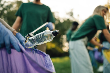 Volunteers picking up plastic bottle trash in park cleanup event