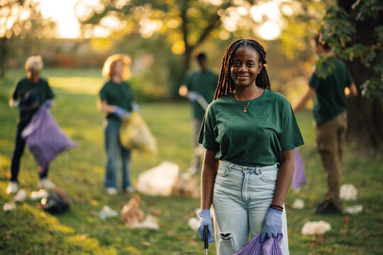 Young woman volunteering collecting trash in park - Powered by Adobe