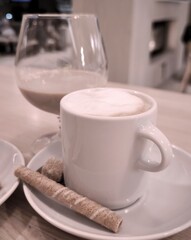 A cozy coffee moment: cappuccino with cookies and liqueur in a glass
