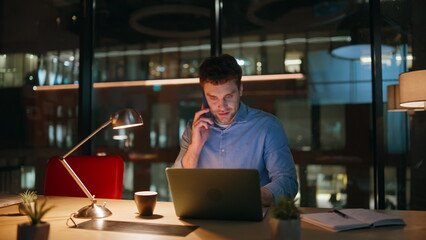 Company professional talking mobile phone at night office closeup. Smiling man