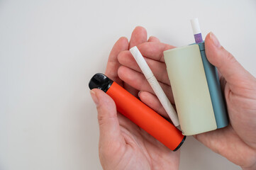 Woman holding regular, electronic cigarette and disposable vape on white background. Tobacco...