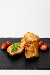 Juicy pieces of grilled chicken served on a black slate plate, garnished with arugula leaves and...