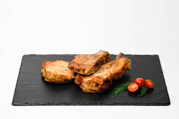 Three juicy grilled pork chops with a golden crust rest on a black stone slab, garnished with fresh dill and halved ripe cherry tomatoes