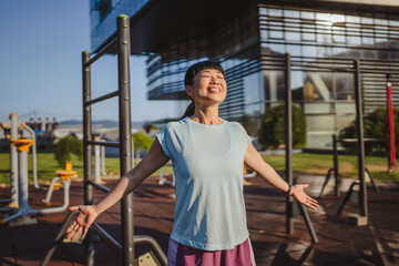 Japanese woman in a sportswear stretching in park before workout