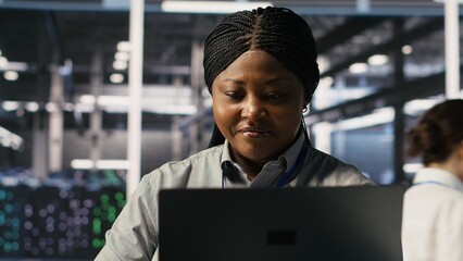 Data center system administrator pleased by neural network outputs after completing software updates. IT expert smiling, looking at laptop screen, optimizing configuration server hub rigs, camera A