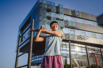 Japanese woman in a sportswear stretching in park before workout
