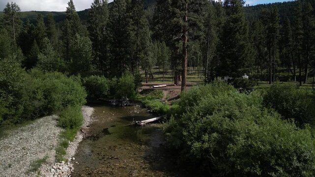Low aerial of RV camped next to Overwich creek in Montana Bitterroot Range in summer