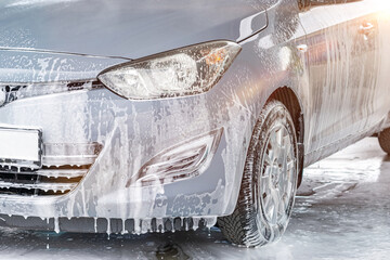 Car wash. Car cleaning foam soap bubbles. Spray water vehicle shine wet.