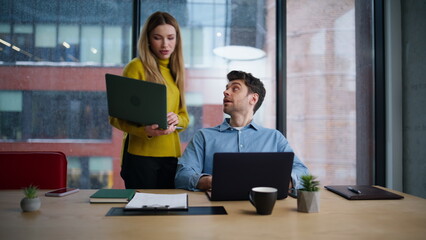 Friendly mentor helping manager in office work showing laptop. Smiling woman man