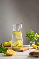 A glass jug with lemonade with lemons, limes and fresh mint, summer drink