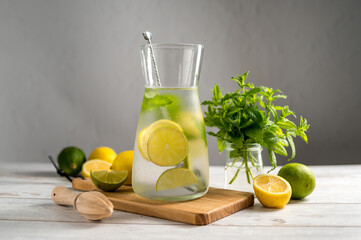 A glass jug with lemonade with lemons, limes and fresh mint, summer drink