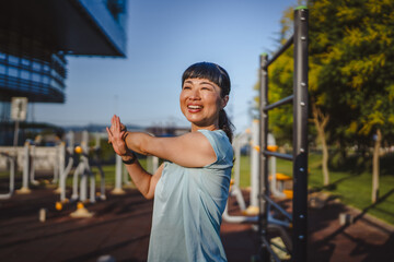 Fototapeta premium Japanese woman in a sportswear stretching in park before workout
