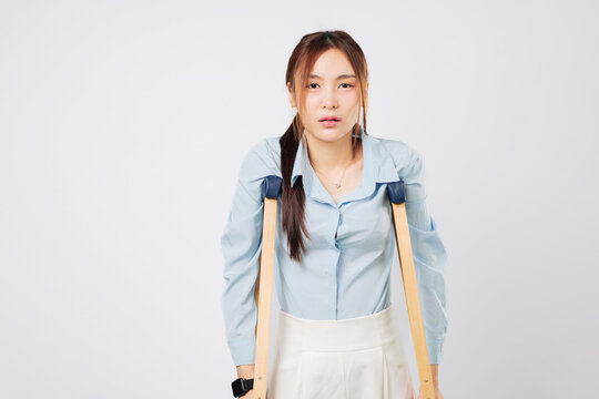 Sad Injured woman walking with crutches, struggling during recovery while holding crutches tightly, showing pain after a bone accident. isolated studio white background - Powered by Adobe