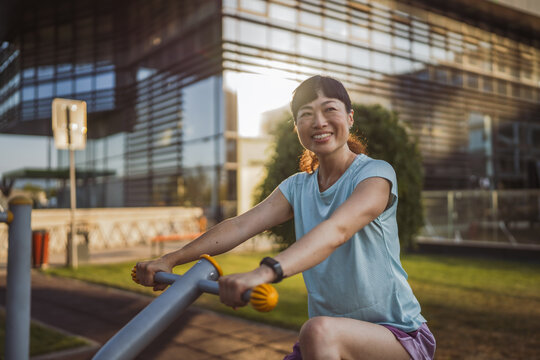 Mature japanese woman exercise on an stationary bike in outdoor gym