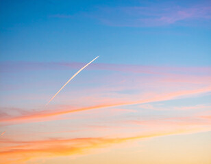 Solitary streak of azure vapor cuts through pastel sky, showcasing beauty of human flight against backdrop of soft pink and blue hues
