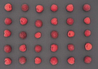 Ripe Raspberries with Green Leaves in Symmetric Composition on graphite Background