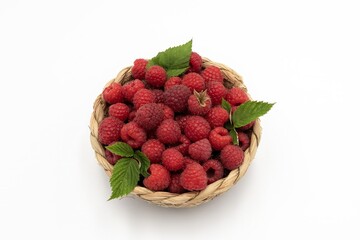 Woven Basket Filled with Ripe Red Raspberries and Green Leaves Isolated on White