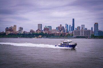 Brooklyn skyline and a boat as seen from Governors Island over the New York Harbor, USA: A cloudy moody day seascape