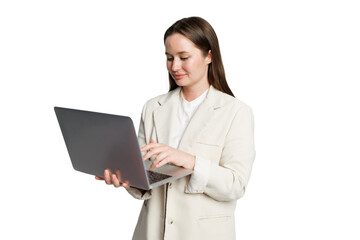 Woman in light blazer working on laptop with a focused expression while standing against a clean white background
