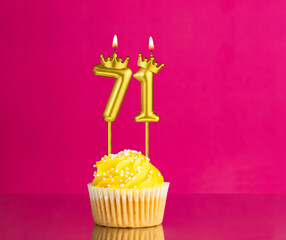 Birthday celebration with number 71 candle - Yellow cupcake on a pink background