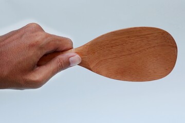 Hand holding wooden ricespoon on white background