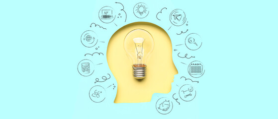 Light bulb visible through cut blue paper in shape of human head on yellow background