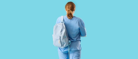 Female medical student with backpack on blue background, back view