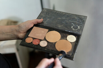 Cosmetic application: hand and brush with face powder palette