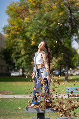Energetic woman with unique style njoying falling leaves