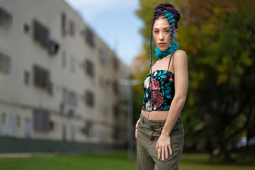 Young woman with creative hairstyle and floral top outdoors