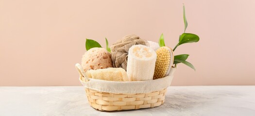 Set of bath sponges in basket on table against beige background