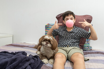 12 year old teenager standing next to his dog and pointing to the gum in his mouth.