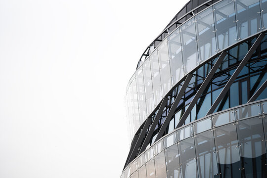 Contemporary office building with a curved glass facade, featuring steel structural elements. The image highlights modern architecture and urban design for commercial property use.