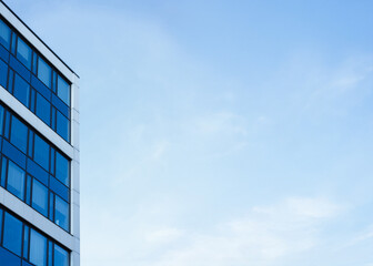 A contemporary office building with glass windows is shown on the left, contrasted by a clear blue...