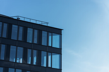 Contemporary office building with large glass windows under clear blue sky, suitable for business or architecture themes. The image highlights modern urban design and corporate environment.