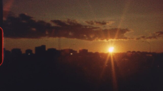 8 mm film - vibrant orange and yellow sunset casting warm glow over metropolitan skyline, featuring nostalgic light leak effect creating vintage aesthetic and serene urban atmosphere