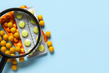 Magnifier with different pills on blue background