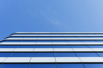 Contemporary office building with reflective glass facade viewed from below, emphasizing modern...