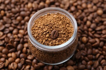 Glass jar with granulated instant coffee on beans, closeup